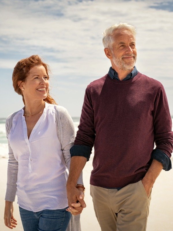 a happy middle-aged man and woman walk together on a beach