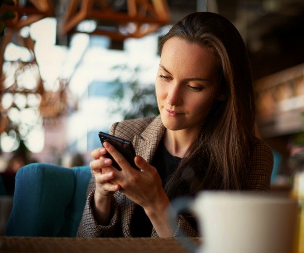 bonus-options-600x500 a woman in a coffee shop uses a dating app on a phone