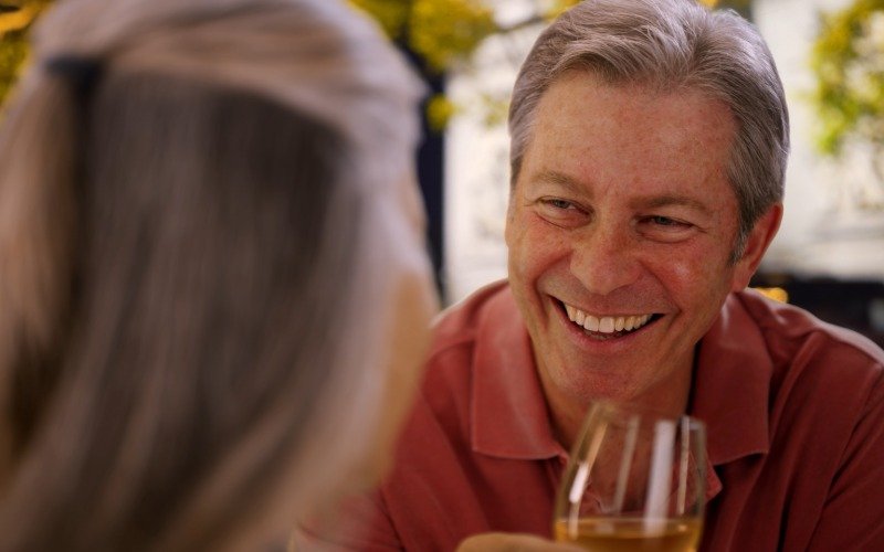 a middle age man smiles happily on a date with a dating app match