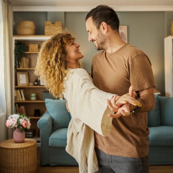a smiling couple dances in a living room